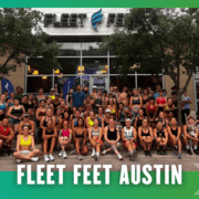 A large, diverse group of people in athletic wear pose and smile outside the Fleet Feet Austin store after a Friday Morning Run, surrounded by trees, with the store’s logo visible above the entrance. Austin Marathon Half Marathon & 5K