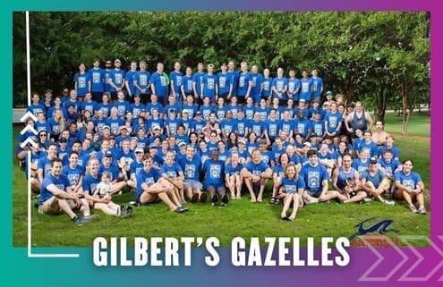 A large group of people wearing matching blue shirts pose for a group photo on grass with trees in the background, representing their running club. Text at the bottom reads "GILBERT'S GAZELLES" with a small gazelle logo on the right. Austin Marathon Half Marathon & 5K