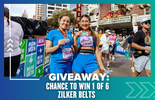 Two smiling women in athletic wear stand holding medals and water bottles at a marathon finish line. Behind them, participants walk by and a banner advertises a Giveaway to win 1 of 6 Zilker Belts. Austin Marathon Half Marathon & 5K