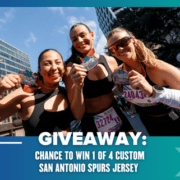 Three smiling runners hold up medals at an outdoor race event. Text reads: "GIVEAWAY: Chance to win 1 of 4 custom San Antonio Spurs jerseys." Urban buildings and trees can be seen in the background. Austin Marathon Half Marathon & 5K