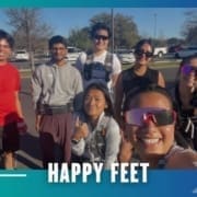 A group of seven smiling people pose outdoors in athletic wear under sunny skies, representing the Buda Running Club. Text at the bottom reads "HAPPY FEET." The image is framed with a blue and teal border and graphics. Austin Marathon Half Marathon & 5K