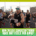 A group of runners participates in a race on a city street, with sunlight and tall buildings in the background. Text at the bottom reads, "How to stay consistent with training when race day feels far away. Austin Marathon Half Marathon & 5K