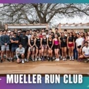 A large group of people in athletic wear pose together and smile for a photo on a wooden deck outdoors. The text reads "Mueller Running Club Group Run" with colorful borders and trees in the background. Austin Marathon Half Marathon & 5K