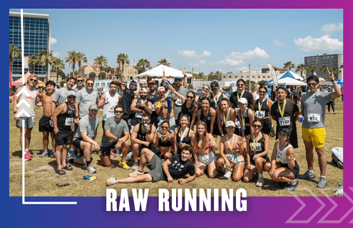 A large group of smiling runners pose together outdoors on grass after a Group Run race, wearing medals and athletic gear, with tents, palm trees, and buildings in the background. Text reads "RAW RUNNING. Austin Marathon Half Marathon & 5K