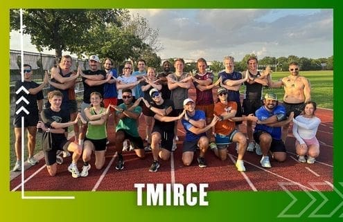 A group of people from the Buda Running Club pose together on a running track, smiling with their arms crossed in front of them. The text "TMIRCE" is at the bottom, featuring a green gradient border and white arrow graphics on the sides. Austin Marathon Half Marathon & 5K