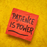 A red sticky note with the words "PATIENCE IS POWER" in bold black letters sits on a textured yellow background, highlighting how patience is an underrated skill, much like in marathon training. Austin Marathon Half Marathon & 5K